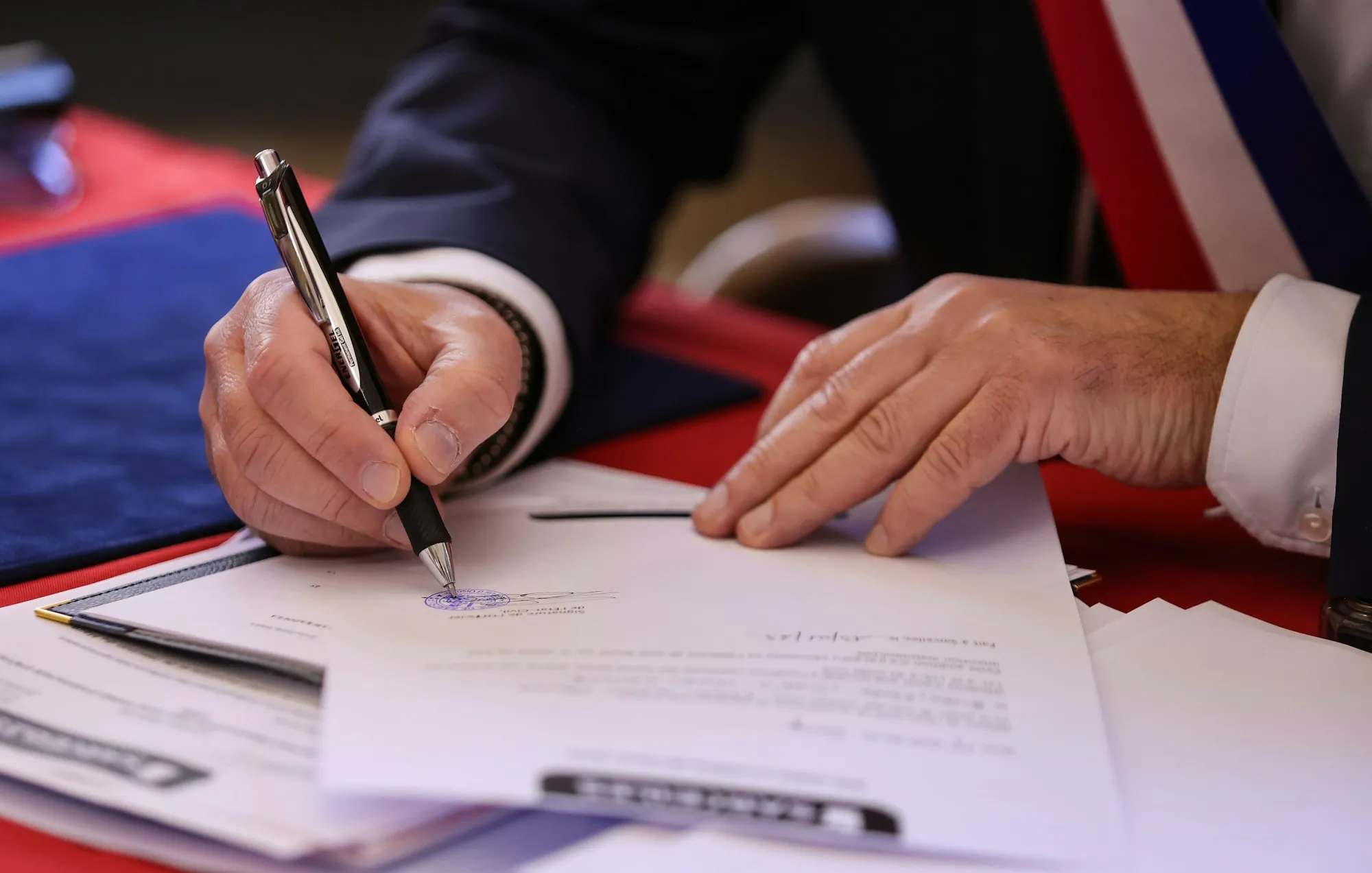Hand signing paperwork on a desk