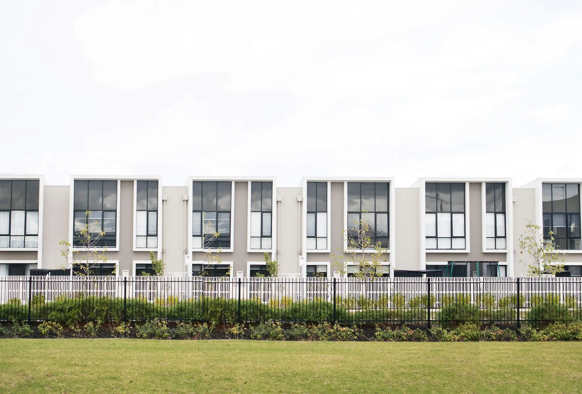 Row of modern white townhouses behind a lawn
